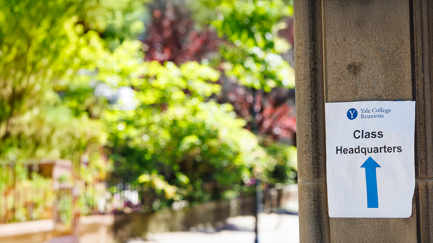 Paper flyer posted on building wall directing attendees which direction Class Headquarters is