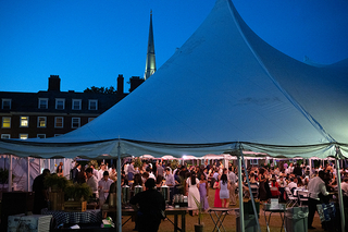 Alumni gathered under tent at night during 2024 reunion event